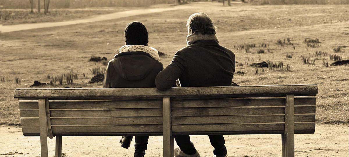Frau und Mann im Gespräch auf einer Parkbank.