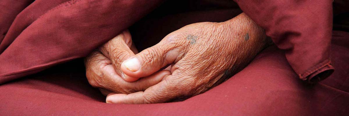 Ineinandergelegte Hände eines Mönchs symbolisieren den Glauben.